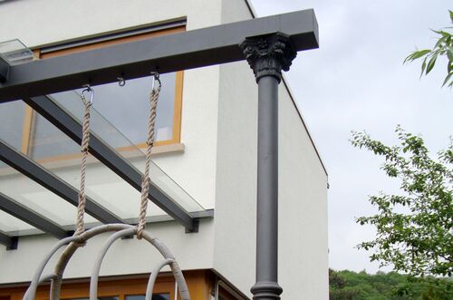 Detailansicht einer eleganten Terrassenüberdachung mit einem dekorativen Säulenstütze und Seilen.