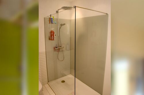 Moderne Dusche mit klaren Trennwänden und Duschzubehör in einem hellen Badezimmer.