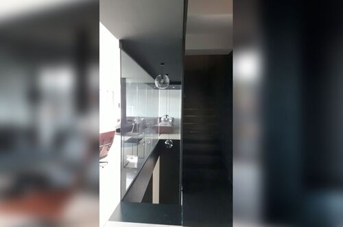 Moderner Treppenaufgang in einem eleganten Raum mit Glasdetails und einem stilvollen Lichtobjekt.