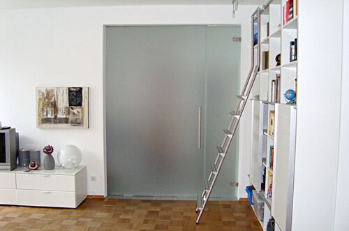 Moderne Schiebetür-Anlage mit einer Aluminiumleiter neben einem Bücherregal in einem hellen Wohnraum.