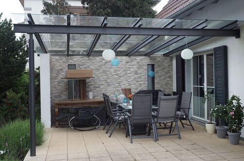 Gemütliche Terrasse mit Überdachung, Esstisch, Stühlen und dekorativen Laternen im modernen Ambiente.