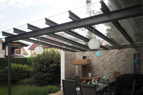Moderne Terrassenüberdachung mit Glasdach und dekorativen Laternen in einem gemütlichen Außenbereich.
